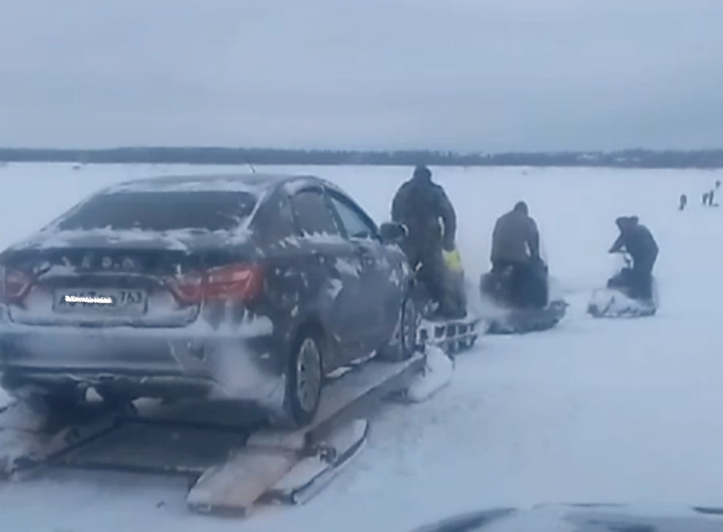 Смельчаки перевозят машины с помощью снегоходов через закрытую переправу на Печоре